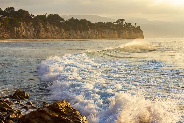 Foaming wave breaking at sunrise with color reflection — Stock Photo, Image