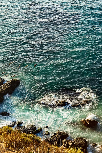 Край скалы соперничает с океанским пространством с волновым действием и кружащимися поролонами и скалами — стоковое фото