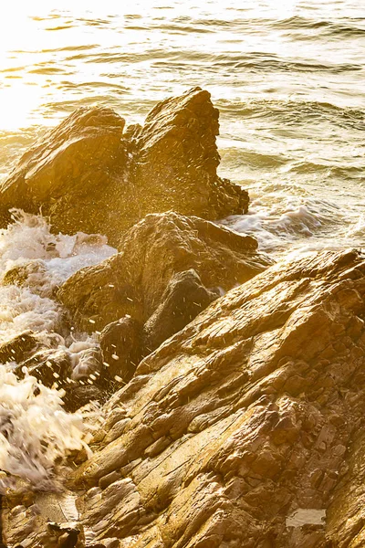 Spruzzi di oceano su massi taglienti con riflesso di luce — Foto Stock