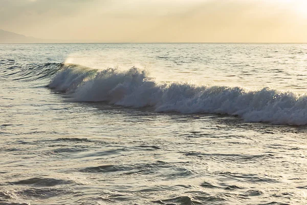 Graue Welle mit Schaum und Rückspülung vor hellblauem Ozean — Stockfoto