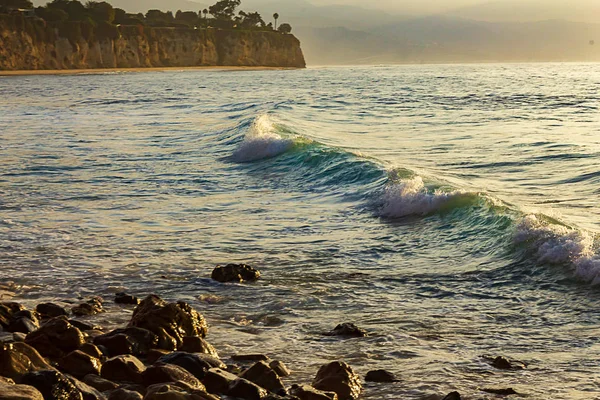 Аква-голубая волна набухает в пену над океанским заливом с каменистым берегом и полуостровом , — стоковое фото