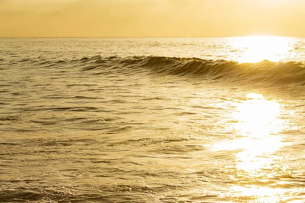 Oceano amarelo com fluxo de luz solar brilhante cruzando onda inchaço sillouetted com extensão do oceano texturizado — Fotografia de Stock