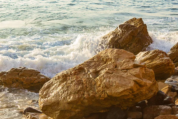 Rocas texturizadas sunlite con espuma rompiendo la ola en la costa rocosa —  Fotos de Stock