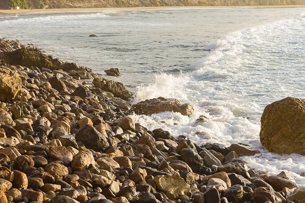 Піниста хвиля, що розбивається на скелястому березі, що проходить валун, підкорити берег — стокове фото