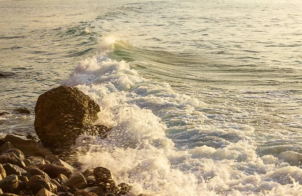 Вспенивающаяся волна врывается вдаль от скалистого берега — стоковое фото
