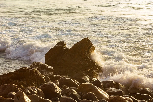 Pěnící vlna na východ slunce s skalnatým pobřežím — Stock fotografie