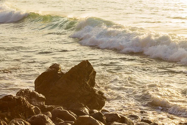 Onda de ruptura com espuma na costa rochosa com reflexão do nascer do sol . — Fotografia de Stock