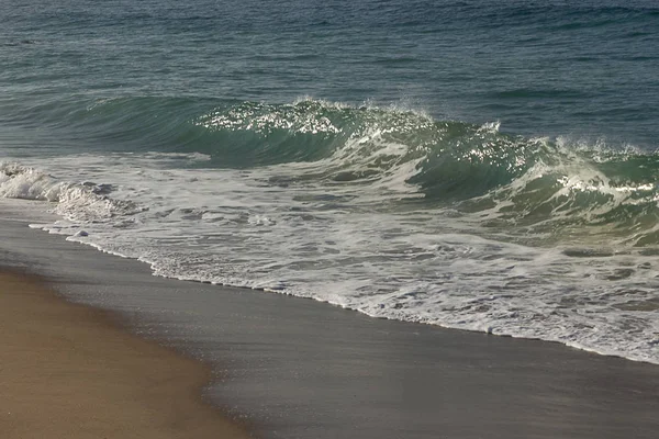 Волна набухает, поднимаясь на краю пены для умывания, с брызгами бекона, на сухом берегу — стоковое фото