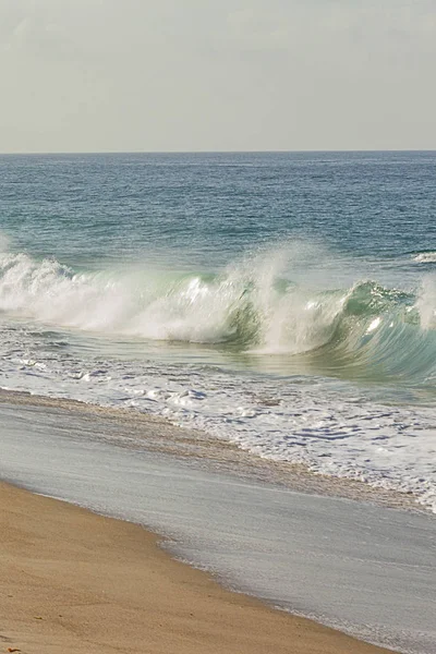 Krachende Welle an sandiger Küste mit Geröll und Eisdecke — Stockfoto