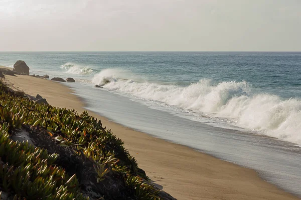 Crista quebrando onda na borda da costa com espuma washback na costa arenosa com pedras — Fotografia de Stock