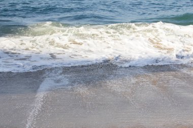 kumlu bir kıyı şeridinde köpük kırma dalgası ve geri yıkama köpük