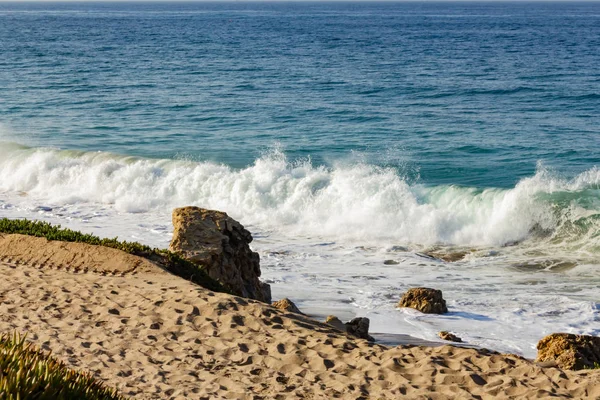 Plätschernde Welle auf Rückspülung und Sandstrand, mit großen Findlingen, Sand — Stockfoto