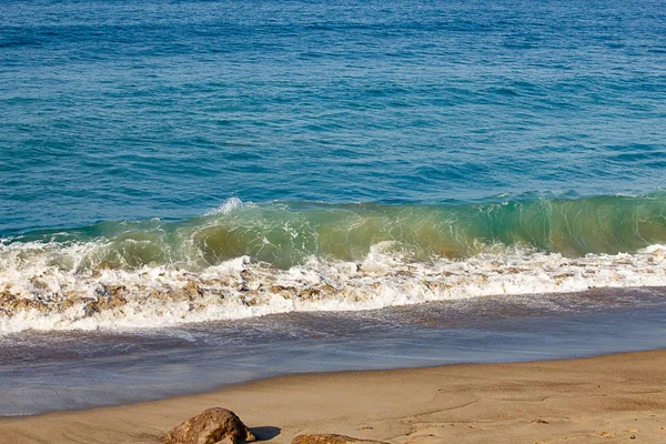 Гребень прорывной волны на берегу края с умывающейся пеной на песчаном берегу — стоковое фото