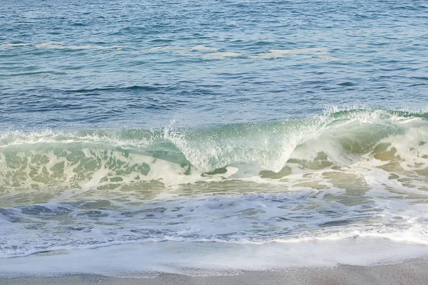 Гребень прорывной волны на берегу края с умывающейся пеной на песчаном берегу — стоковое фото