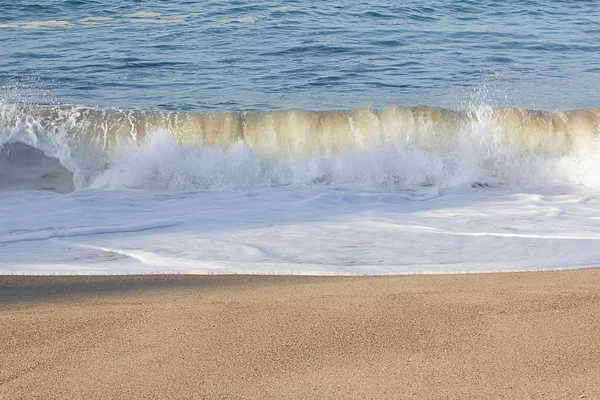 Небольшая прозрачная волна, ломающаяся на песчаной береговой линии с пеной — стоковое фото