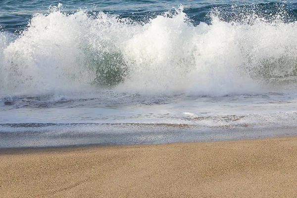 Взрывающаяся волна с всплеском вспенивания на песчаном пляже — стоковое фото