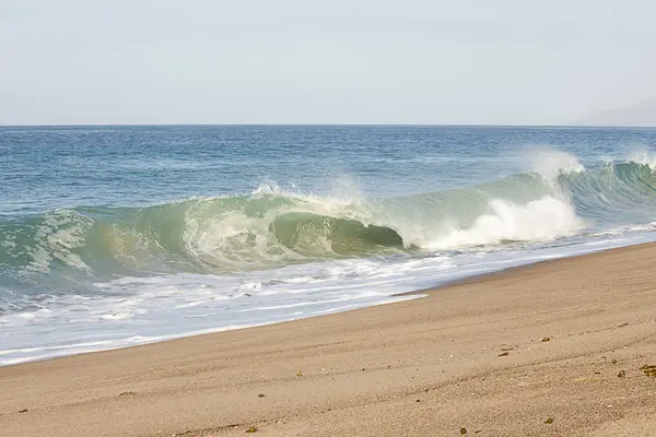 Разбивая трубчатую волну на песчаном пляже с пенной обратной водой, открытое пространство океана — стоковое фото