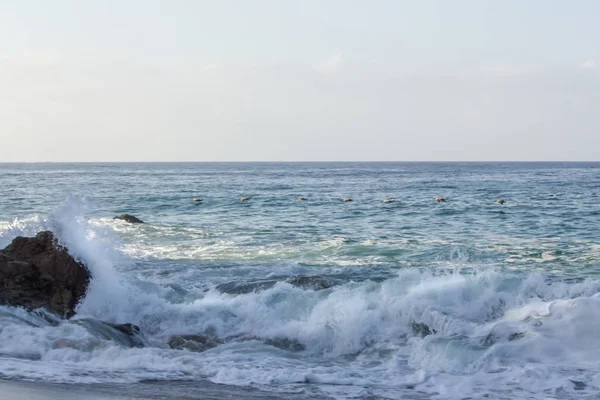 Splashing wave breaking on rock, with swirling foam from breaking wave and returning backwash — стоковое фото