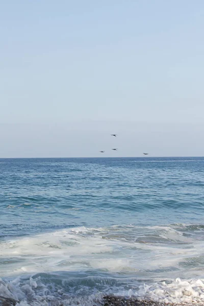 Кружащаяся пена на галечном пляже с открытым океаном к горизонту — стоковое фото