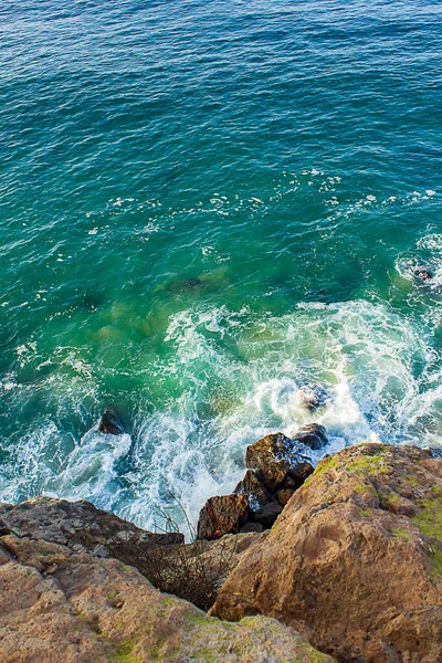 Vista do penhasco de onda e espuma quebrando em rochas na base do penhasco — Fotografia de Stock