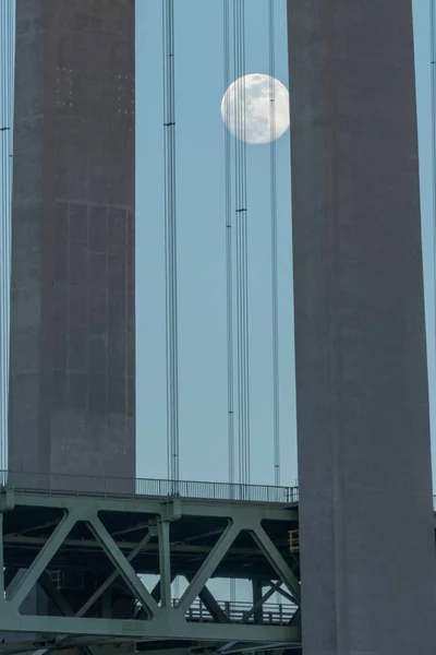 Tidig sort fullmåne över en hängbro — Stockfoto
