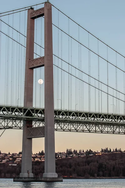 Księżyc w ramce przez most wiszący o zachodzie słońca — Zdjęcie stockowe