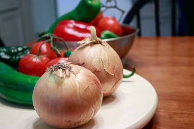 Tüm soğan, yeşil biber, ve bir mutfakta bir masada kırmızı domates