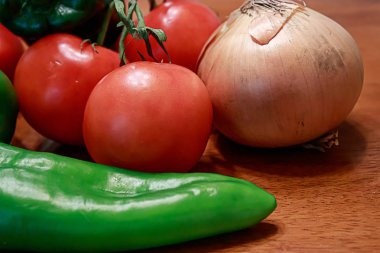 bir mutfakta bir masada kırmızı domates, yeşil biber ve altın soğan