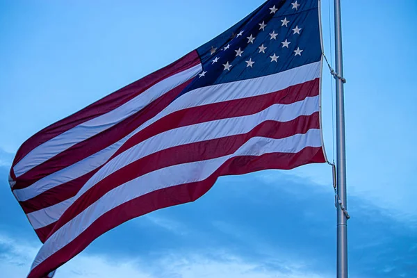 american flag flying high in cloudy sky during spring against blue