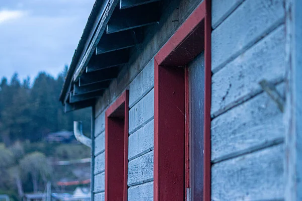 Blaue Holzabstellgleise und rot getrimmte Fenster, gealtert und von Zeit und Wetter geplagt — Stockfoto