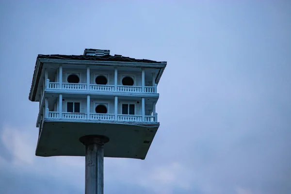 Um birdhouse velho com pilars um envoltório em torno do convés e do telhado em um pólo de metal — Fotografia de Stock
