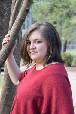 kırmızı gömlekli güzel kız ilkbaharda ağacın yanında duruyor