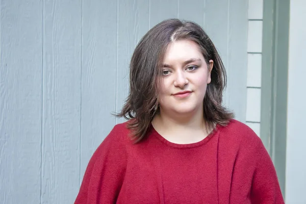 pretty girl smirks at someone from near a home