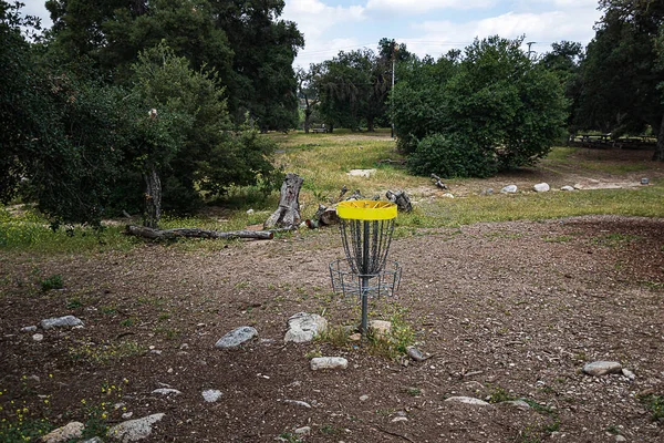 open dry natural park with california live oak trees, rocks, and grass weeds and frisbee golf net