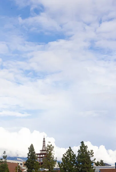Blå himmel med många gigantiska moln med byggnader och träd — Stockfoto