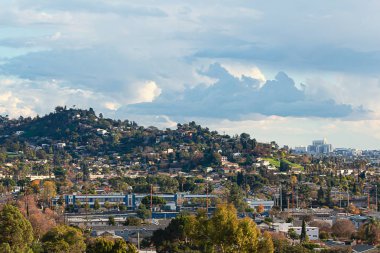 tepeler ve bulutlu mavi gökyüzü ve yamaç evleri ile dökmeyen ve disiduous ağaçları ile şehir scape