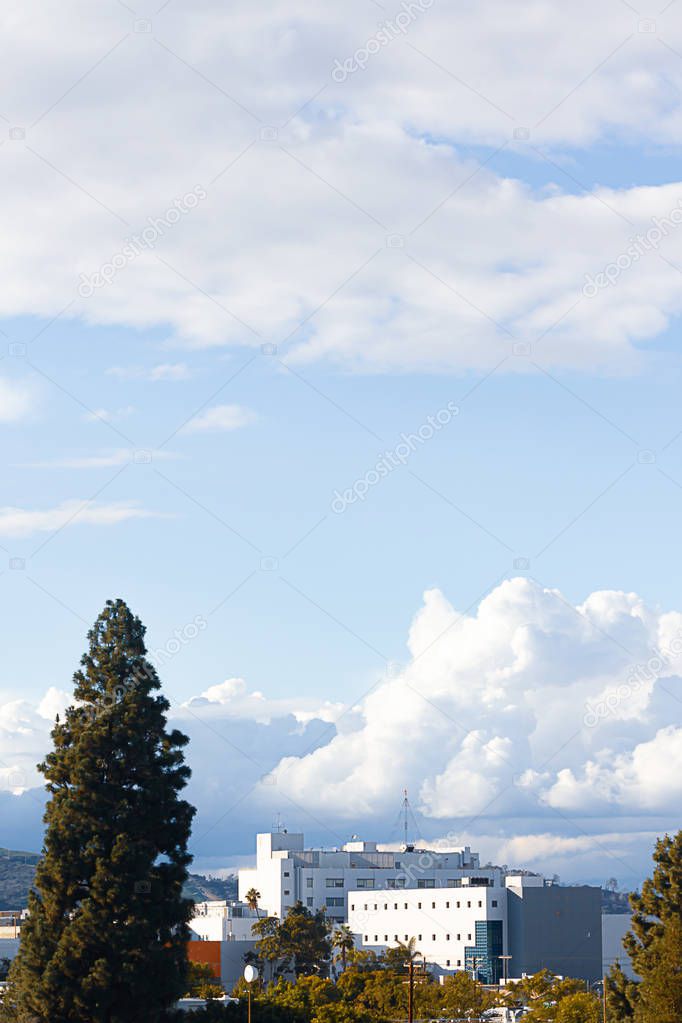 apartments and city buildings with trees mountains blue sky and clouds