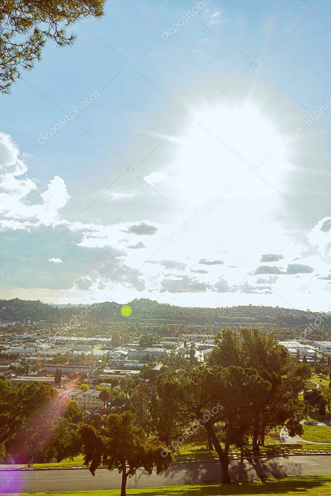 sunflare over panaramic city view with hillsides and trees, homes, businesses