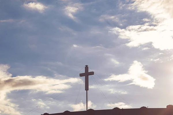 Cruz branca silhueta no céu azul com cúmulo brilhante, nuvens de nimbus — Fotografia de Stock