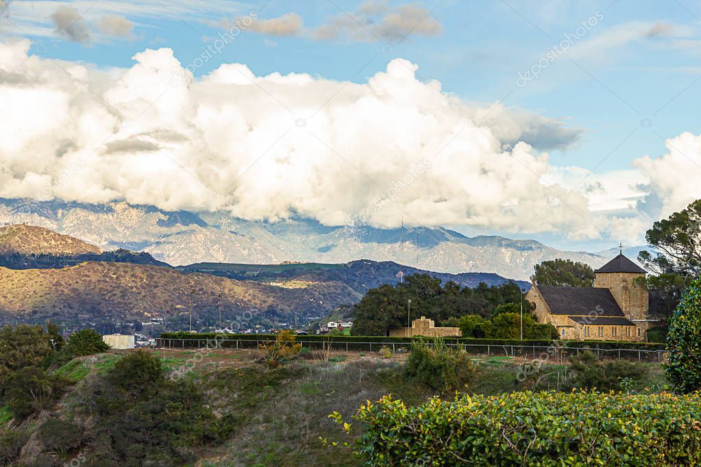 hillside view of hills home roads with san gabriel mountains cloudscape, brick church