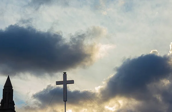 Silhueta de touret edifício e cruz contra céu nublado por do sol — Fotografia de Stock