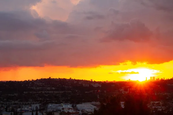 Distant downtown towers in sunset glow with panoramic view of yellow sunrays on red glow — Stock Photo, Image