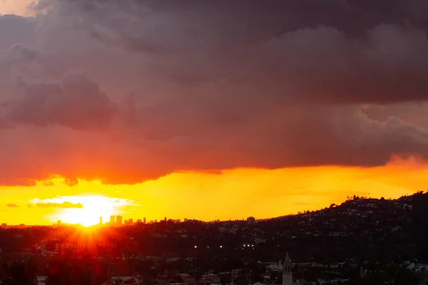 Distant downtown towers in sunset glow with panoramic view of yellow sunrays on red glow — Stock Photo, Image