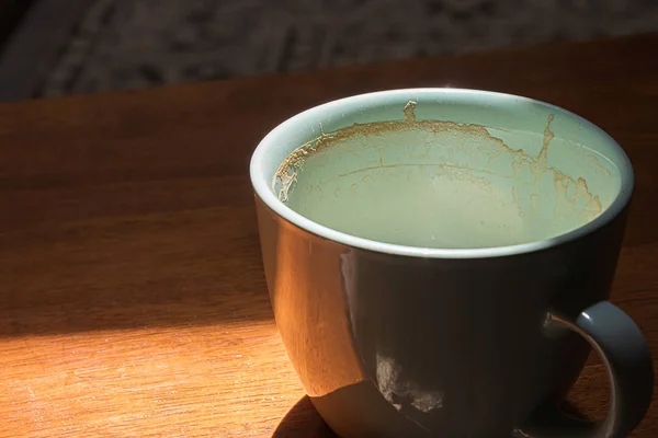 Small blue coffee mug sitting used and empty in a sunbeam in a dimly lit room — Stock Photo, Image