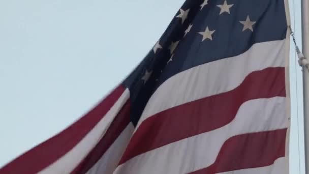 Bandera americana ondeando en la parte superior de un asta de bandera alta — Vídeo de stock