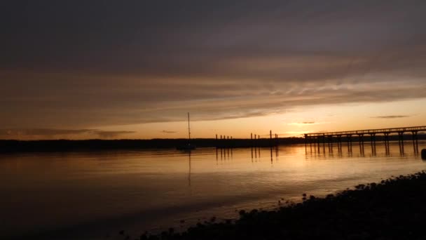 Jetée longue menant au-dessus de l'eau au coucher du soleil — Video