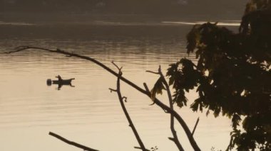 Gün batımında teknede balık tutan kişi.