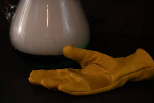 Un guante amarillo junto a la jarra de hielo seco sobre fondo negro —  Fotos de Stock