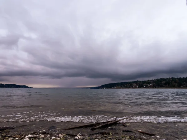 Storm clouds building over rocky pebble covered shore