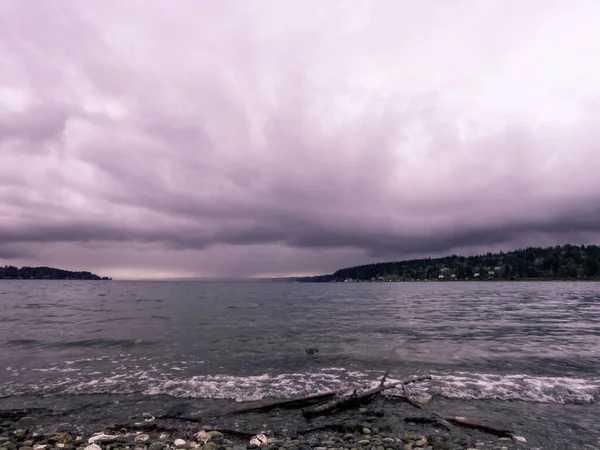 Storm moln bygga över stenig sten täckt strand — Stockfoto
